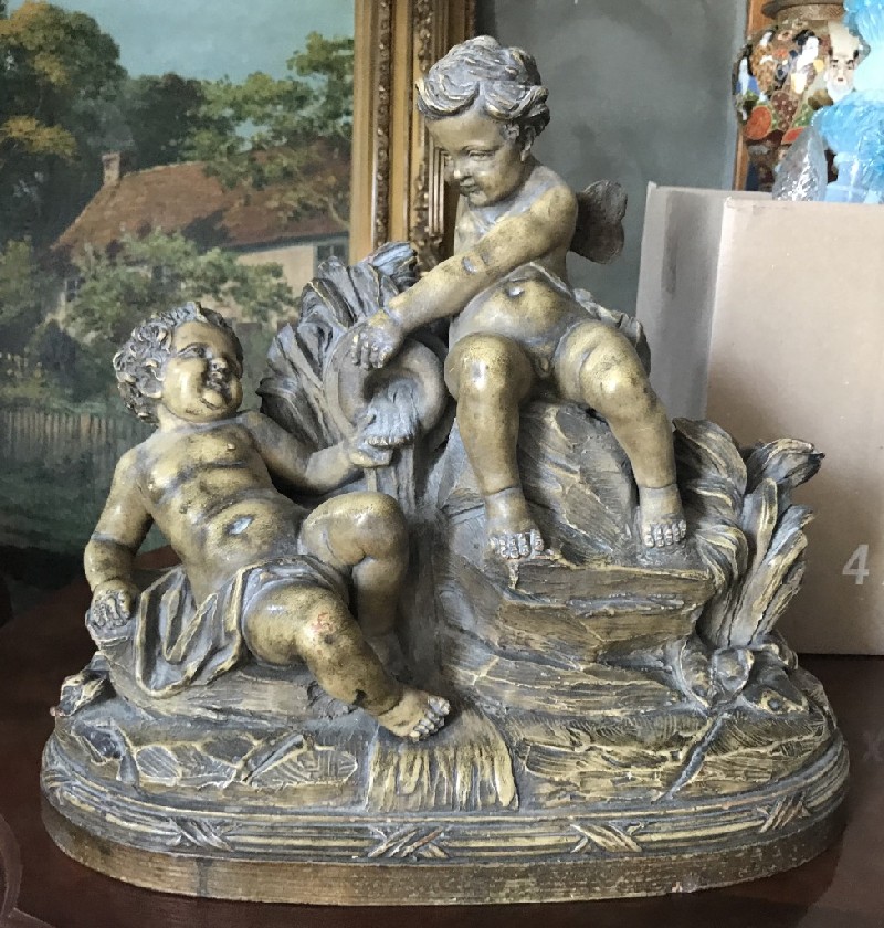 French signed terracotta statue of three cupids playing on a rock.