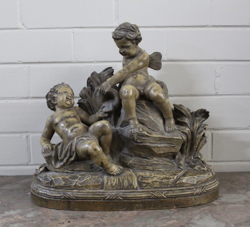 Impressive French terracotta figure of three cupids at play on a rock, signed.