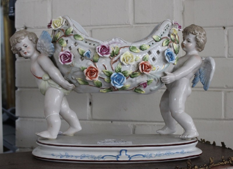 Decorative French porcealin center table comport bowl supported by two cupidsand decorated with flowers. Price $625
